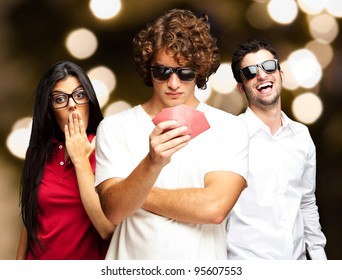 Young Man Playing Poker With Friends Against A Abstract Lights Background