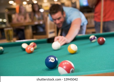 Young Man Playing Pool In A Bar (focus On Pool Table)