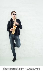 Young Man Playing Sax Laening Against A Wall