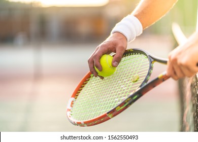 Young Man Playing Tennis Outdoors. Close Up Of Tennis Player Hands Holding Racket With Ball. Professional Tennis Player Hitting The Ball. Sport Concept.