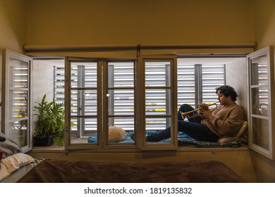 Young Man Playing Trumpet At Home