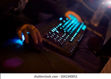 Young man playing video game with laptop. Gamer with computer in dark or late at night. Hands on mouse and keyboard. Competitive gaming, electronic sports and esports.