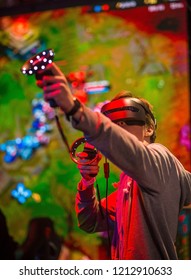 Young Man Playing A Virtual Reality Game, While Wearing Goggles At A Venue.