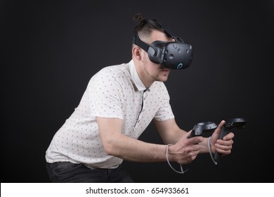 Young Man Playing With Virtual Reality Video Game In Studio