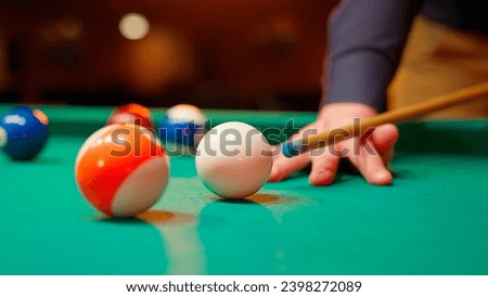 A young man plays American billiards. Russian billiards, an American in a billiards club and bar. Dark colors in the billiard club. A man pockets snooker balls.
