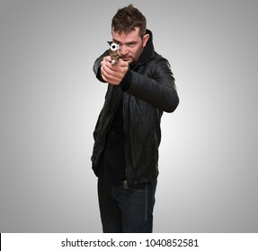 young man pointing with gun against a grey background