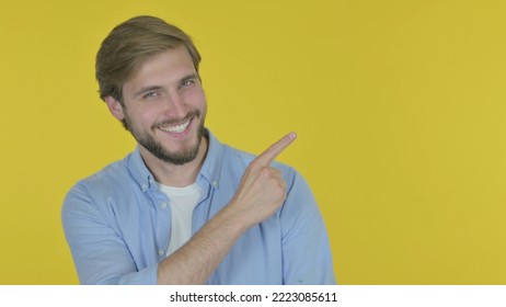 Young Man Pointing on Side on Yellow Background - Shutterstock ID 2223085611