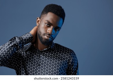 Young man in polka dot shirt looking stressed with hand on head, facing personal or workrelated challenges