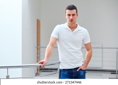 Young Man In A Polo Shirt Stands Leaning On Railing