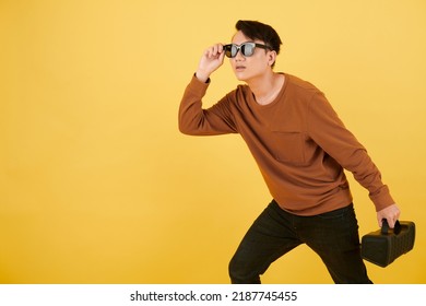 Young Man With Portable Speaker Adjusting Sunglasses And Looking Away