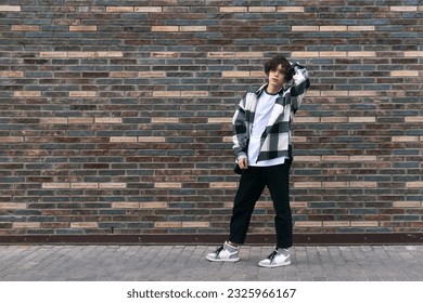 young man posing against a brick wall