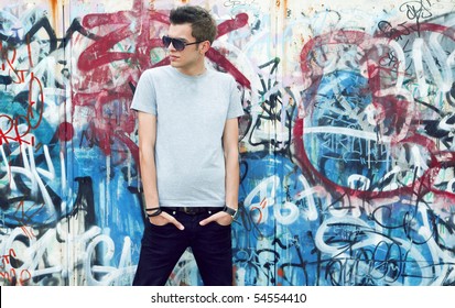  young man posing in front of a colorful graffiti wall