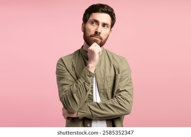 Young man posing with pensive expression, looking incredulous, posing in studio over pink background. People emotions concept