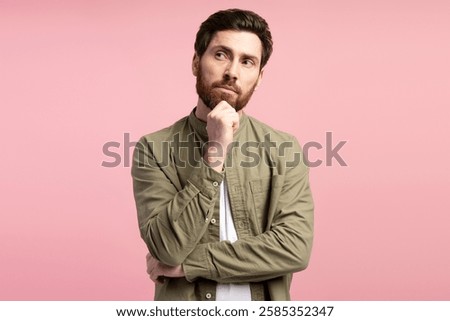 Young man posing with pensive expression, looking incredulous, posing in studio over pink background. People emotions concept