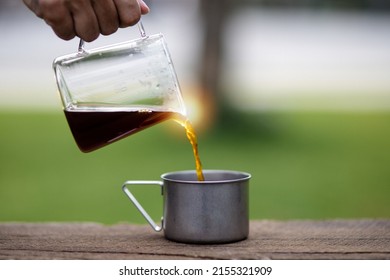 Young Man Pouring Coffee In Cup, Morning Breakfast On Open Air. Traveler Camping For First Time, New Experience To Rest With Tent. Nature, Leisure, No Rush, Peace And Calmness Concept