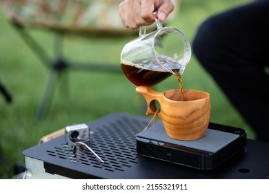 Young Man Pouring Coffee In Cup, Morning Breakfast On Open Air. Traveler Camping For First Time, New Experience To Rest With Tent. Nature, Leisure, No Rush, Peace And Calmness Concept