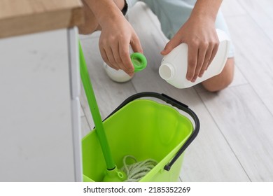 Young man pouring detergent into bucket in kitchen, closeup - Powered by Shutterstock