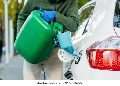 Young Man Pouring Gasoline Into An Empty Fuel Tank From A Plastic Green Canister. Close Up	
