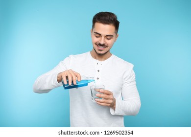 Young man pouring mouthwash from bottle into glass on color background. Teeth and oral care - Shutterstock ID 1269502354