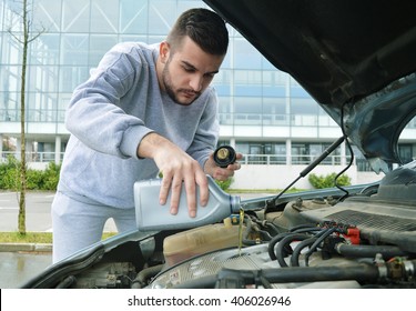 Young Man Pouring Oil Into The Car.