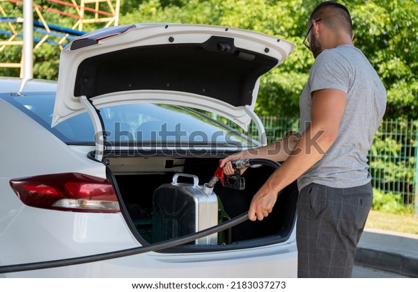 A young\
man pours gasoline into the gas tank of a white car.A young man\
pumps gasoline into a gas tank. Fuel and oil crisis. The concept of\
gasoline prices and the oil\
crisis.