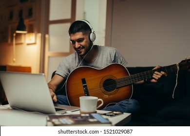 young man practice to play guitar at his home - Powered by Shutterstock