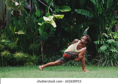 Young Man Practice Yoga In He Green Tropical Garden During Retreat Vacation In Bali, Stretching, Meditation, Wellness