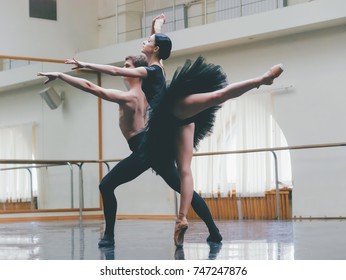 Young Man Practicing In Classical Ballet With Young Beautiful Woman In Black Tutu Clothing In The Gym. Minimalism Interior, Dancing Sensual Dance.