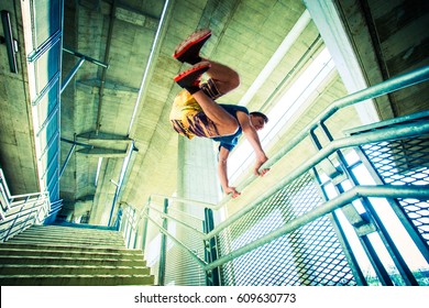 young man practicing parkour jumping on stairs with metal fence, city extreme sport concept shot from below - Powered by Shutterstock