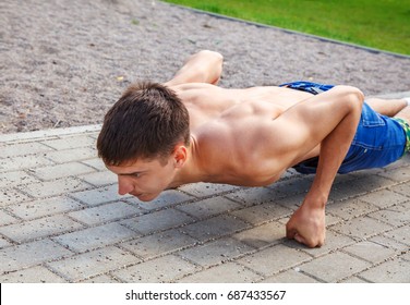 young man practicing of push-up inthe park on summer day closeup