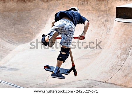 Young man practicing Scootering (Freestyle Scootering) in the new SkatePark of the central park of Igualada, Barcelona, Spain