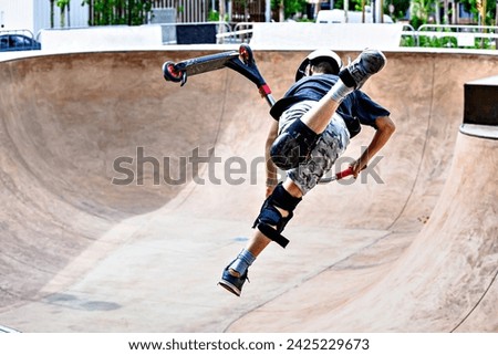 Young man practicing Scootering (Freestyle Scootering) in the new SkatePark of the central park of Igualada, Barcelona, Spain
