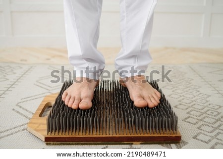 Young man practicing of standing on nails, copy space.  Person legs on sadhu board yoga meditation foot massage