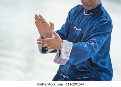 Young man practicing traditional Tai Chi Chuan, Tai Ji and Qi gong in the park for healthy, traditional chinese martial arts concept.