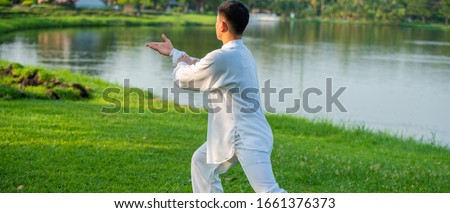 Young man practicing traditional Tai Chi Chuan, Tai Ji and Qi gong in the park for healthy, traditional Chinese martial arts concept.