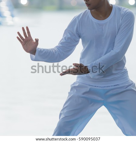 Young man practicing traditional Tai Chi Chuan, Tai Ji  and Qi gong in the park for healthy, traditional chinese martial arts concept.