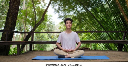 Young man practicing yoga and meditating at open yoga studio with beautiful nature view in background. - Powered by Shutterstock
