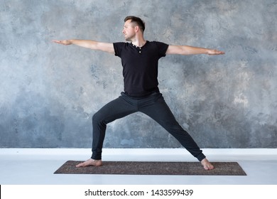 Young man practicing yoga in studio doing Warrior 2 pose, Viradhadrasana - Powered by Shutterstock