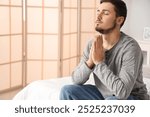 Young man praying in bedroom