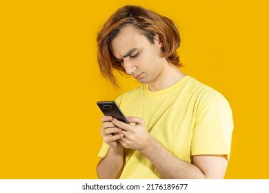 Young Man Prep Student With Long Hair. 20s Guy With Smartphone On A Yellow Background.