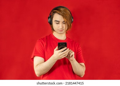 Young Man Prep Student With Long Hair. 20s Guy With Smartphone On A Red Background.