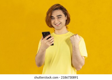 Young Man Prep Student With Long Hair. 20s Guy With Smartphone On A Yellow Background.