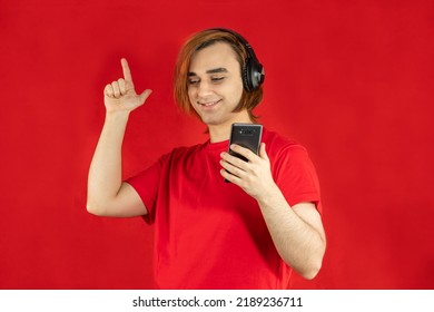 Young Man Prep Student With Long Hair. 20s Guy With Smartphone On A Red Background.