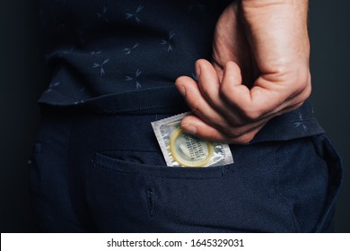 young man prepares for a romantic date: puts condoms in the pocket of classic pants.  body part: men's tight ass. Remember to protect. safe sex, AIDS. office worker holding condoms in hand