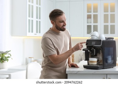 Young man preparing fresh aromatic coffee with modern machine in kitchen - Powered by Shutterstock