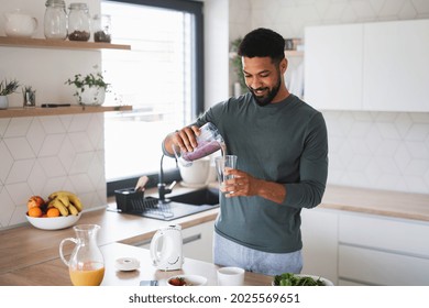 Young man preparing healthy breakfast indoors at home, pouring milk shake into glass. - Powered by Shutterstock