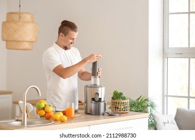 Young man preparing healthy fruit juice in kitchen - Powered by Shutterstock