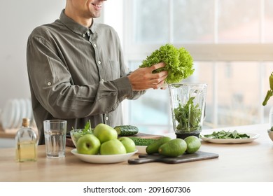 Young Man Preparing Healthy Green Smoothie In Kitchen