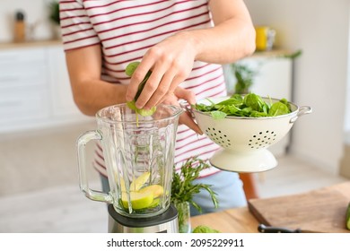 Young Man Preparing Healthy Green Smoothie In Kitchen