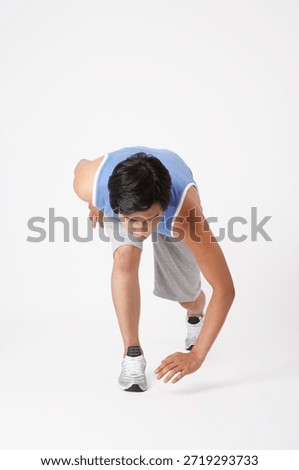 Young man preparing to run in a straight posture indoors with focus on feet and hands in motion